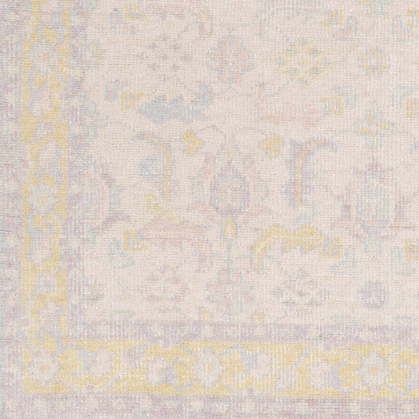 Close-up of the Navarino Area Rug showing its traditional pattern, light beige background, and accents of dusty pink, denim, and mustard. Swatch