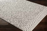 Close-up of the Naylor Beige/Charcoal Rug. Features a geometric triangle pattern and a border of circles. Farmhouse style. Corner