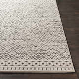 Close-up of Naylor Beige/Charcoal Rug showing geometric triangle pattern and border detail on dark wood floor. Front