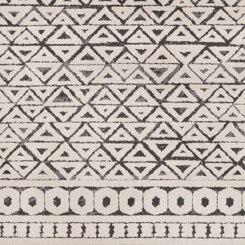 Close-up of Naylor Beige/Charcoal Rug. Features a geometric triangle and circle pattern in neutral beige and charcoal tones. Swatch