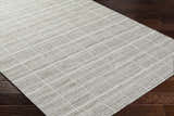 Close-up of the hand-woven Nissa Checkered Area Rug. Light gray wool rug with an off-white checkered pattern. Corner