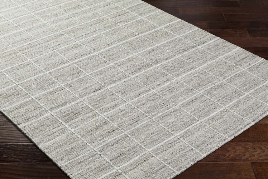 Close-up of the hand-woven Nissa Checkered Area Rug. Light gray wool rug with an off-white checkered pattern. Corner