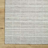 Close-up of the hand woven Nissa Checkered Area Rug. Light gray, medium gray, and off-white wool with a subtle checkered pattern. Corner