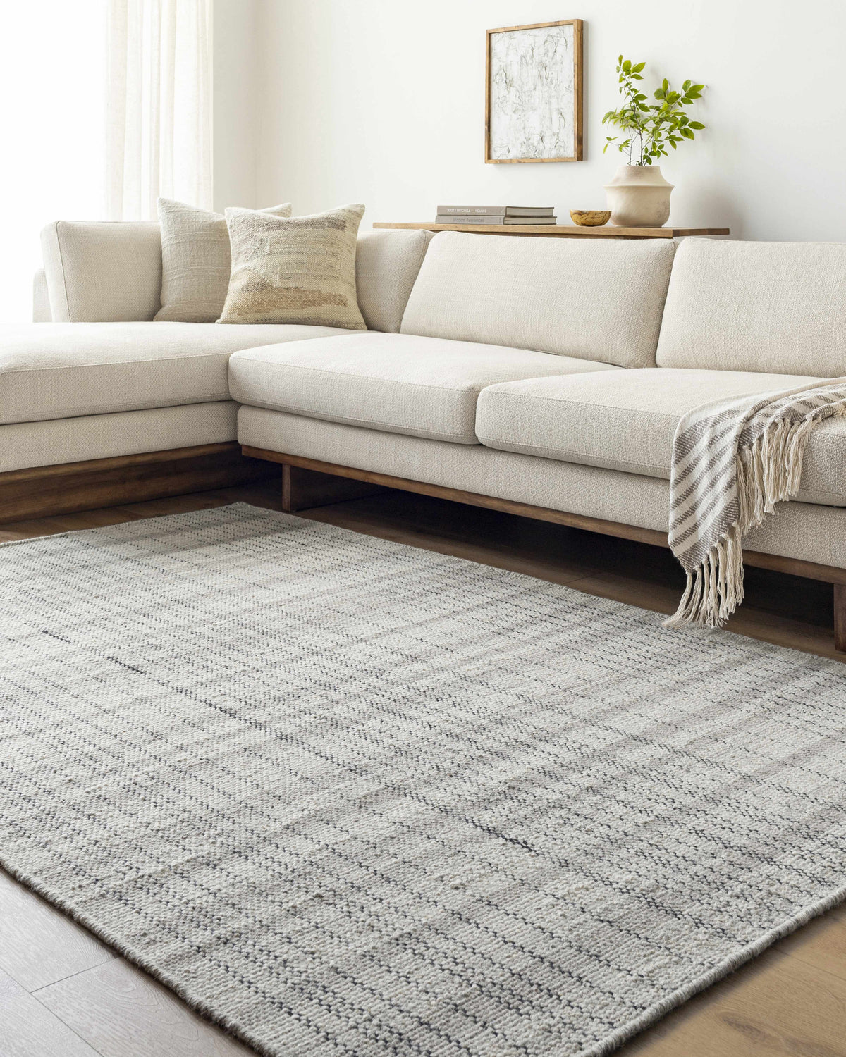Living room scene with a light beige sectional sofa and the Nissa Blue Gray Checkered Area Rug on hardwood floors. Roomscene-Rectangle