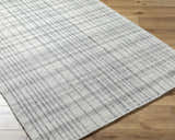 Close-up of the hand woven Nissa Blue Gray Checkered Area Rug on wood floor. Light silver, sage, and slate blue wool rug. Corner
