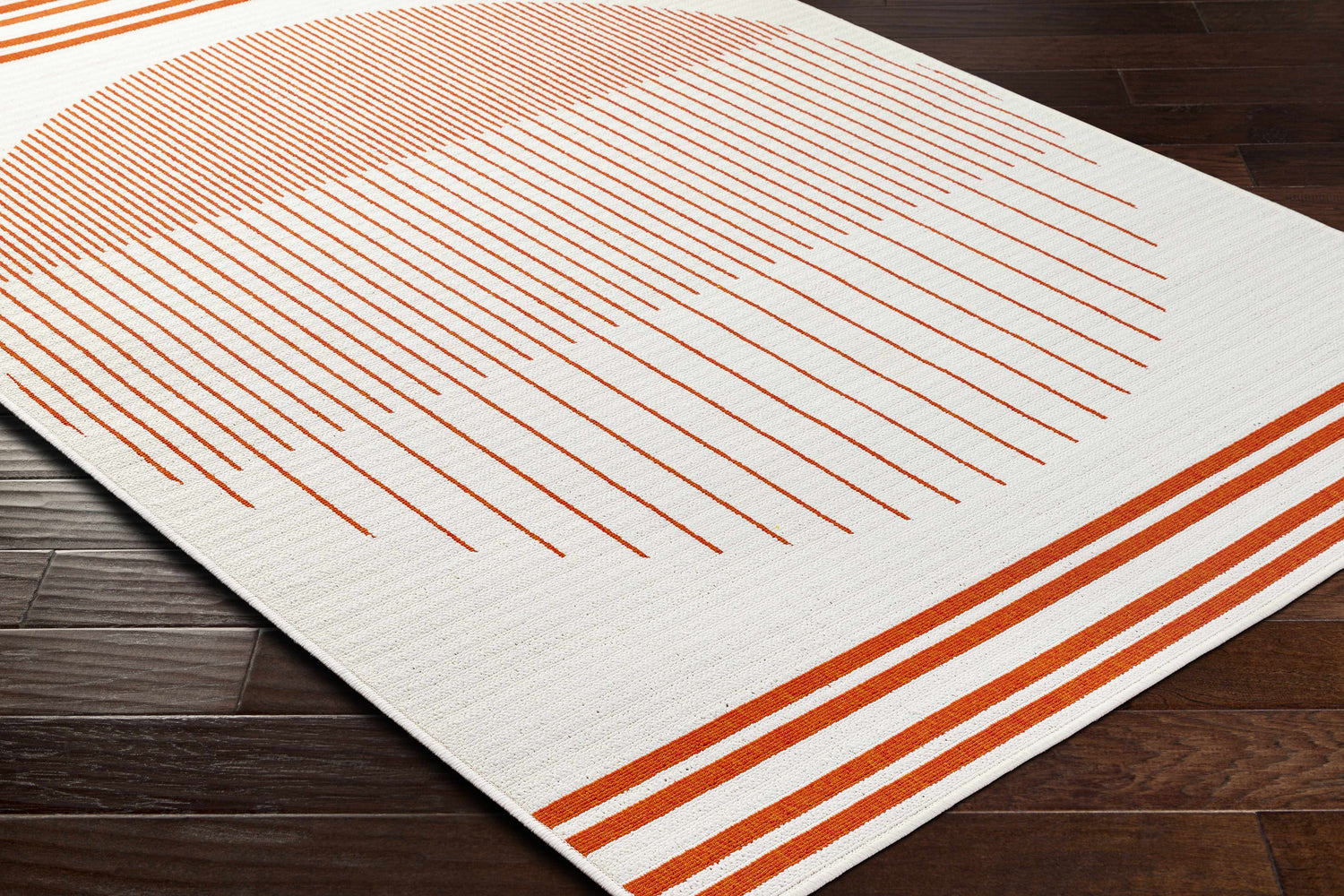 Close-up of the Nabil Cream Area Rug with a modern orange linear and circular pattern on dark wood floors. Corner