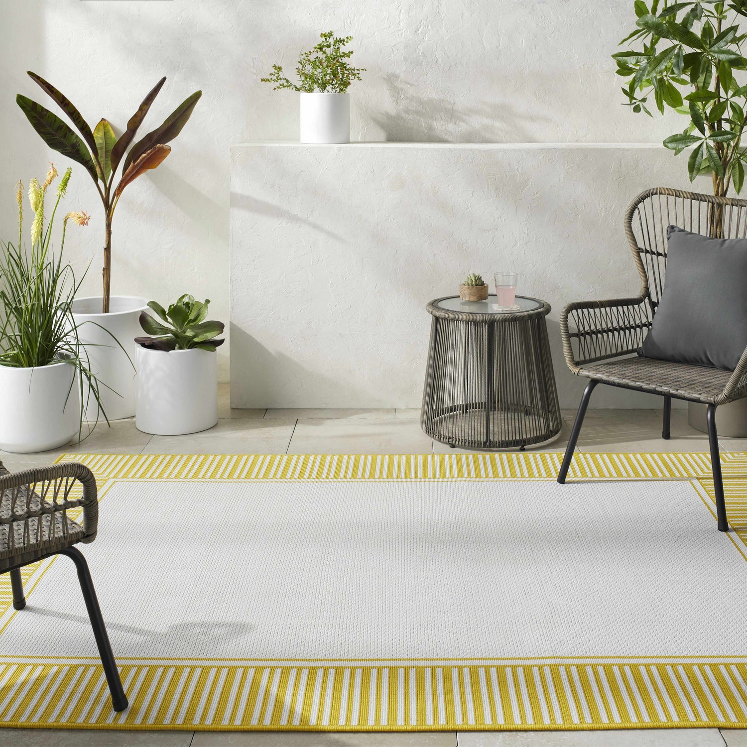 Outdoor patio scene with a cream Nadir Area Rug featuring a yellow striped border. Roomscene-Rectangle