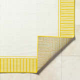 Close-up of Nadir Area Rug. Cream rug with yellow and white striped border. Machine woven olefin rug. Fold