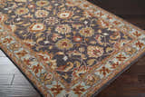 Close-up of the hand-tufted Cherryfield 1004 wool area rug. Features a floral pattern in beige, burnt orange, and slate blue. Corner