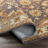 Close-up of the hand-tufted Cherryfield 1004 wool rug. Features a traditional floral pattern in beige, burnt orange, and slate. Fold