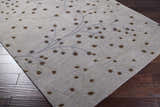 Close-up of Sage Brown Elsu Area Rug with a floral design in brown, sage, and gray on a wood floor. Corner