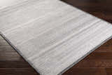 Close-up of Nettleham Silver Viscose Rug showing woven texture and charcoal, gray, and silver tones on dark wood floor. Corner