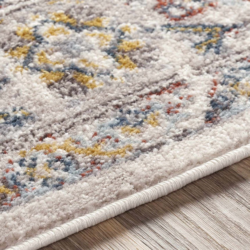 Close-up of the Newkirk Area Rug showing its cream base with brick red, charcoal, mustard, and blue traditional pattern. Texture