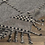 Close-up of the hand woven Ninderry Wool Area Rug. Black and cream rug with braided tassels. Bohemian farmhouse style. Fold