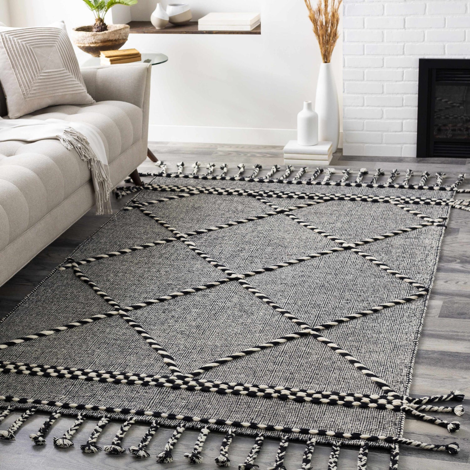 Living room scene with the Ninderry Wool Area Rug, showcasing its black and cream diamond pattern and braided fringe. Roomscene-Rectangle