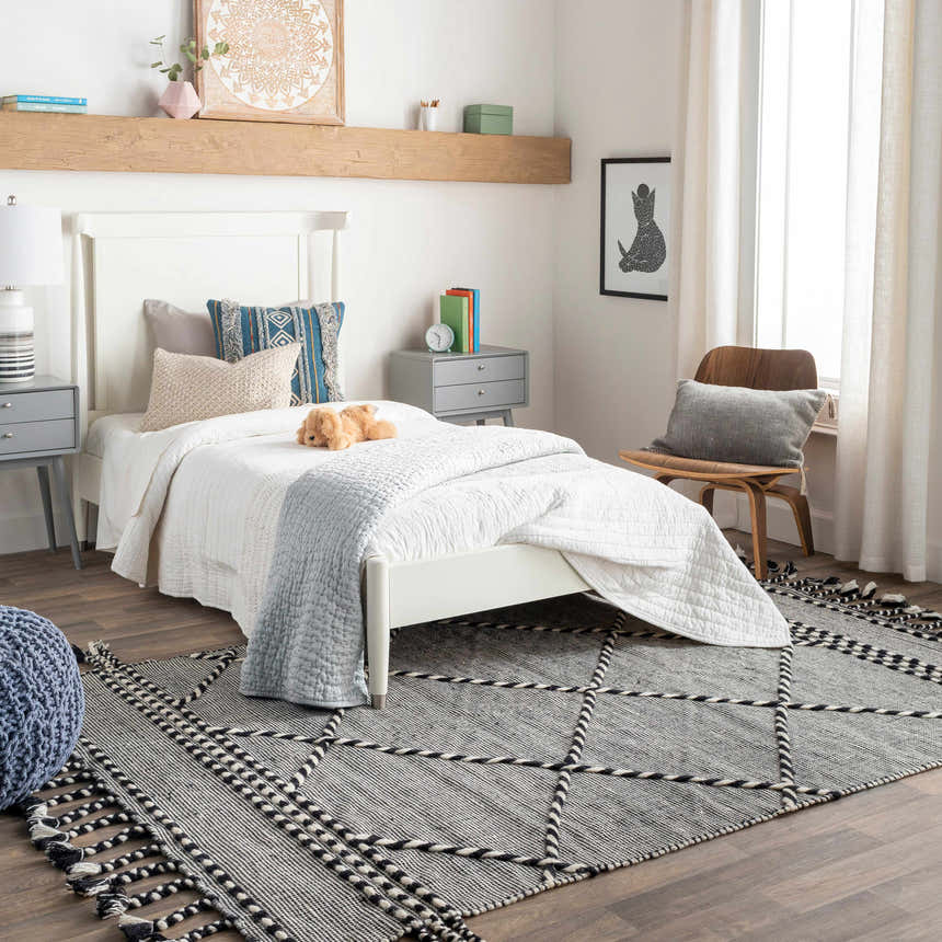 Bedroom scene with a black and cream Ninderry Wool Area Rug, white bed, gray nightstands, and wood accents. Roomscene-Rectangle
