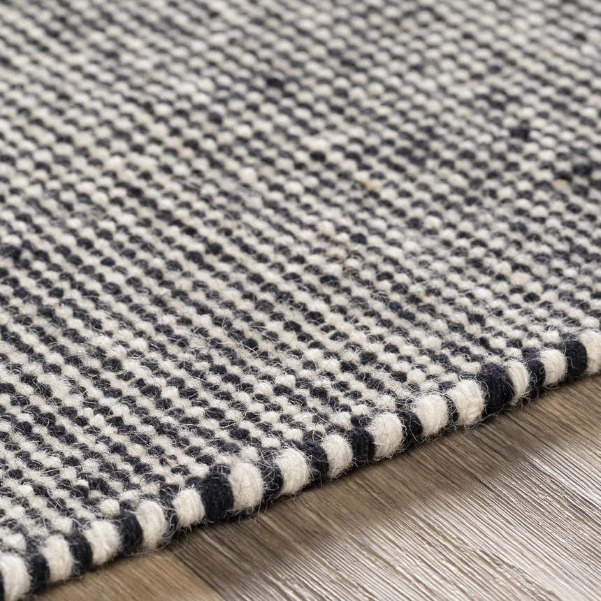 Close-up of the hand woven Ninderry Wool Area Rug. Black and cream wool creates a textured, bohemian pattern. Texture