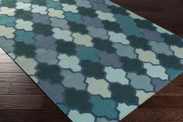 Close-up of the hand woven Node Area Carpet. Features a contemporary quatrefoil pattern in dark blue, emerald, sage, and seafoam. Corner