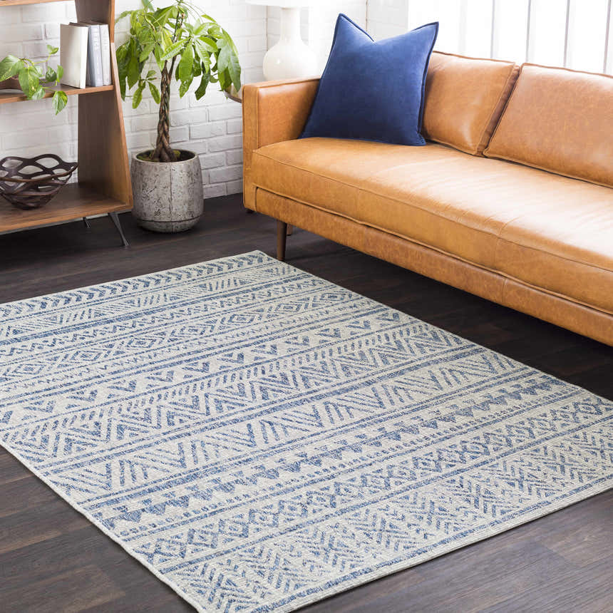 Living room with a tan leather sofa and blue Novato All Over Pattern Performance Rug. Roomscene-Rectangle
