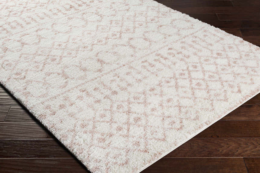 Close-up of plush Narrogin Area Rug. Cream shag rug with subtle blush geometric pattern. Bohemian style. Corner