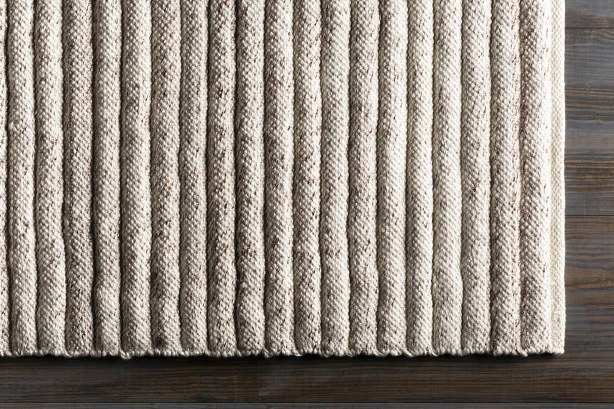 Close-up of the hand woven Nuangola Area Rug. Dark brown and off white textured stripes on a rectangle rug. Corner