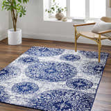 Living room scene with navy and pale blue Nubia Area Rug, woven chair, wood floors, and natural light. Roomscene-Rectangle
