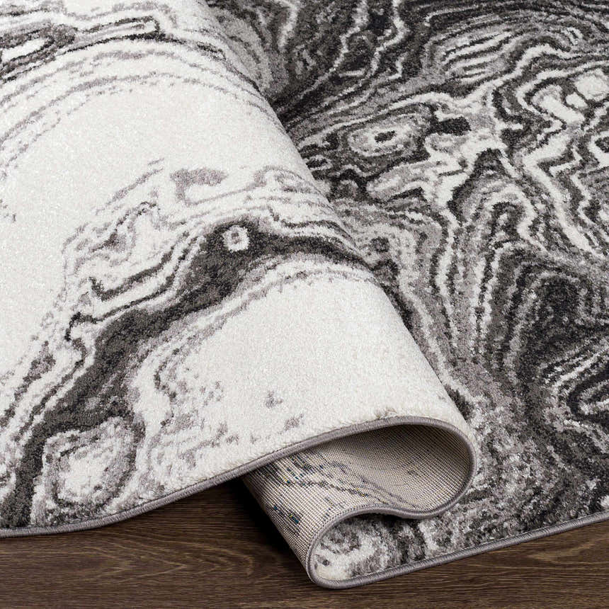 Close-up of the Nuevo Black Marble Carpet showing its black, cream, and gray contemporary marble-like pattern. Fold