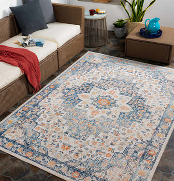 Outdoor patio scene with wicker furniture and the Invermere rug in cream, navy, and rust floral pattern. Roomscene-Rectangle
