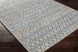 Close-up of Newbern Outdoor Rug. Blue geometric pattern on taupe background. Machine woven polypropylene rug. Corner