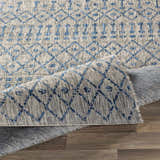 Close-up of the Newbern Outdoor Rug showing a blue and taupe geometric pattern and machine-woven texture. Fold