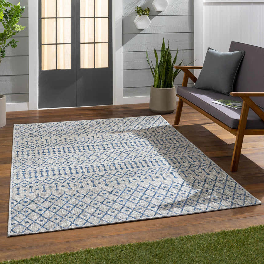Outdoor patio scene with a blue and white geometric Newbern Outdoor Rug, wood floors, and gray loveseat. Roomscene-Rectangle