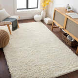 Living room scene with a cream Oakridge Area Rug, wood cabinet, chair, and woven pouf. Roomscene-Rectangle