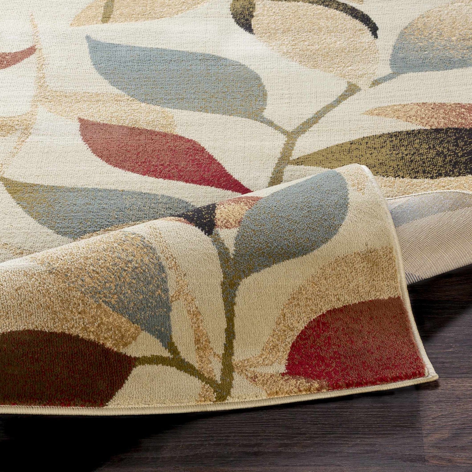 Close up of the Ober Fall Leaves Rug showing its leaf pattern and colors like red, blue, brown, and green. Fold
