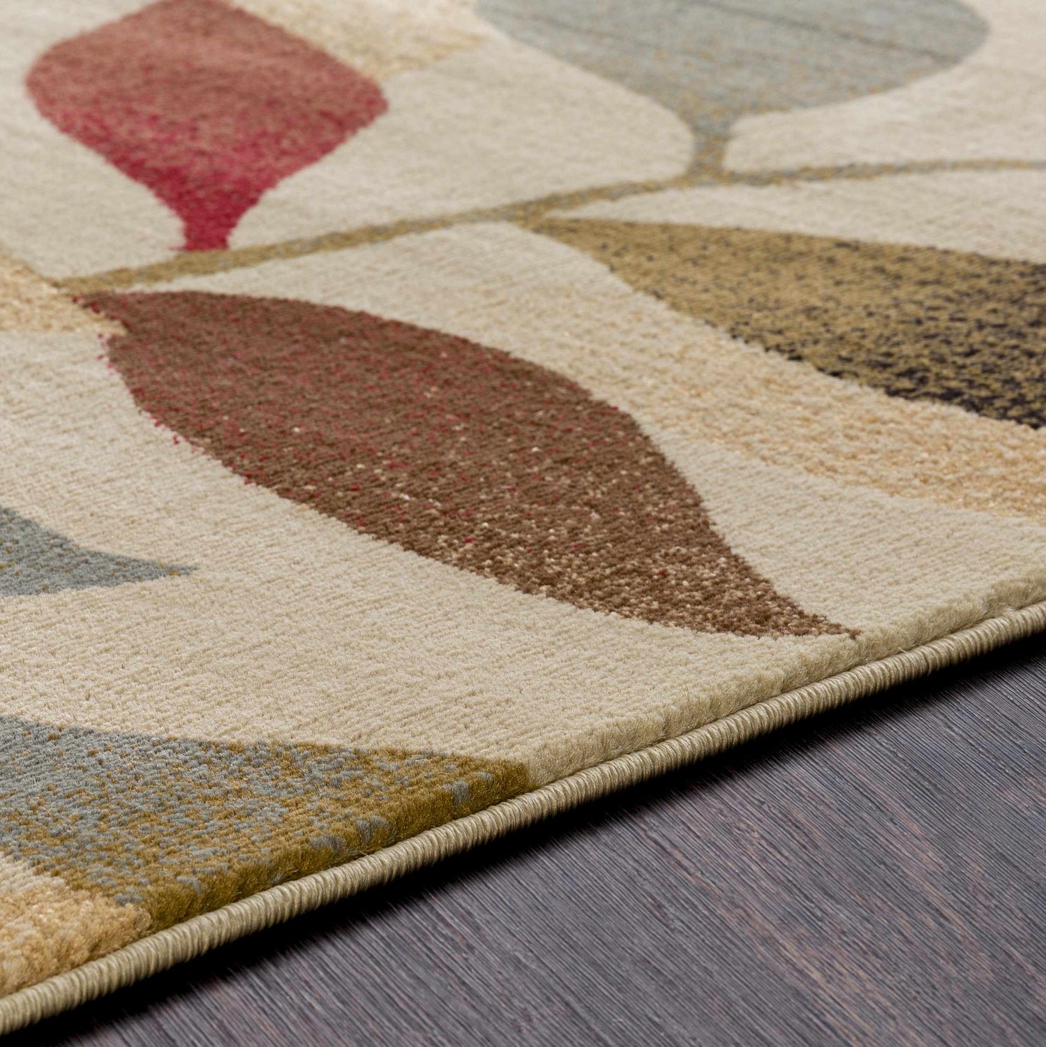 Close-up of the Ober Fall Leaves Rug, a machine-woven rug with a contemporary leaf pattern in red, brown, green, and mustard tones. Texture