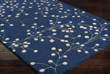 Close-up of the Blue Elsu Area Rug, a hand-tufted wool rug with a botanical design in ink blue and tan. Corner