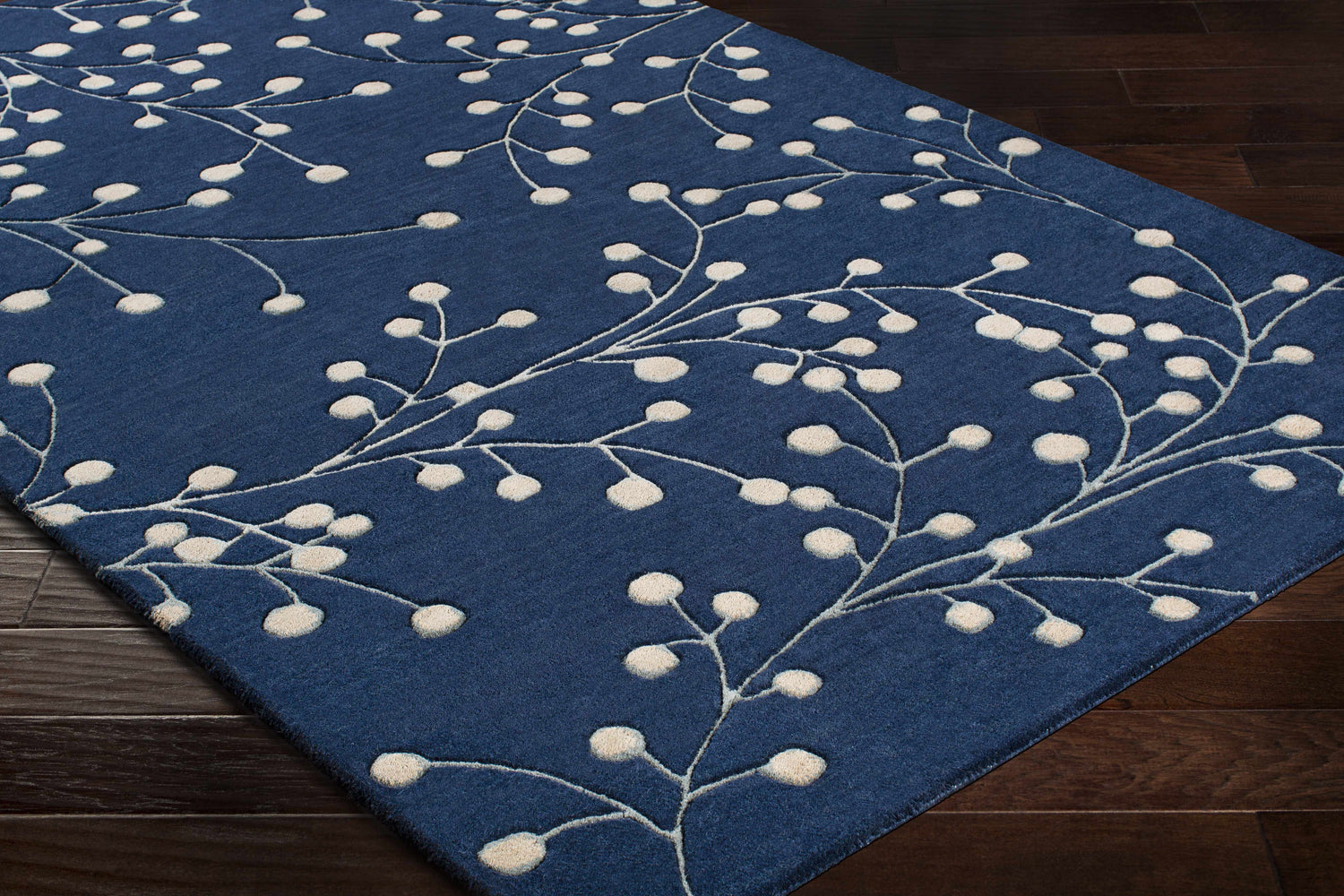 Close-up of the Blue Elsu Area Rug, a hand-tufted wool rug with a botanical design in ink blue and tan. Corner