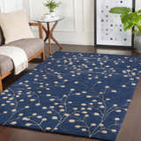 Living room scene with a blue Elsu Area Rug featuring a tan floral pattern on dark wood floors. Roomscene-Rectangle