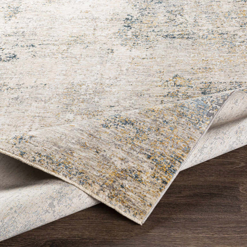 Close-up of the Odell Abstract Luxe Fringe Rug, featuring dark blue, light blue, gray, and mustard colors. Fold