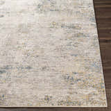 Close-up of the Odell Abstract Luxe Fringe Rug. Features dark blue, light blue, gray, and mustard colors. Front
