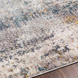 Close up of the Odell Abstract Luxe Fringe Rug, featuring dark blue, light blue, gray, and mustard colors. Texture
