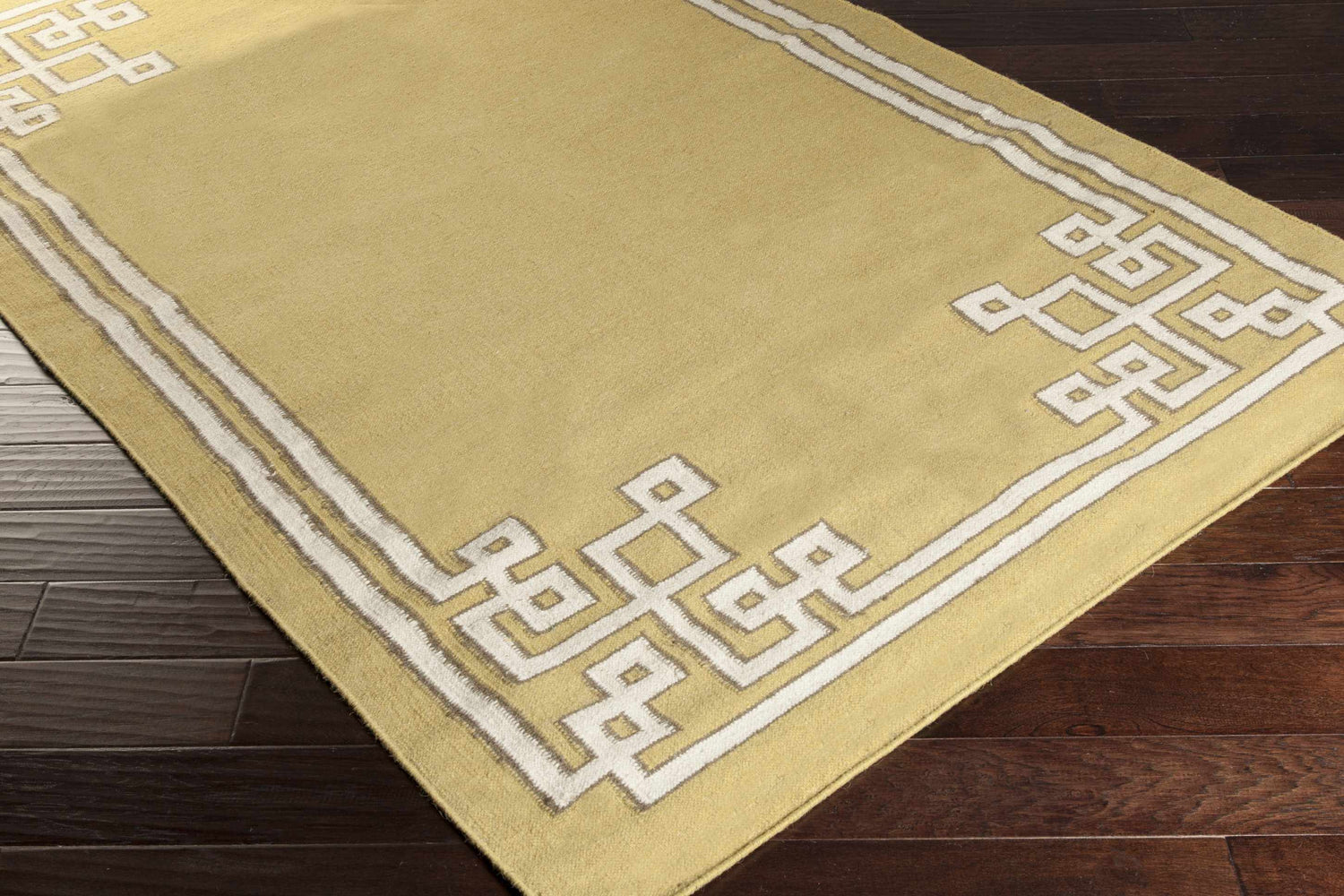 Close-up of the hand woven Ogle Area Rug. Light beige wool rug with a contemporary white geometric border. Corner