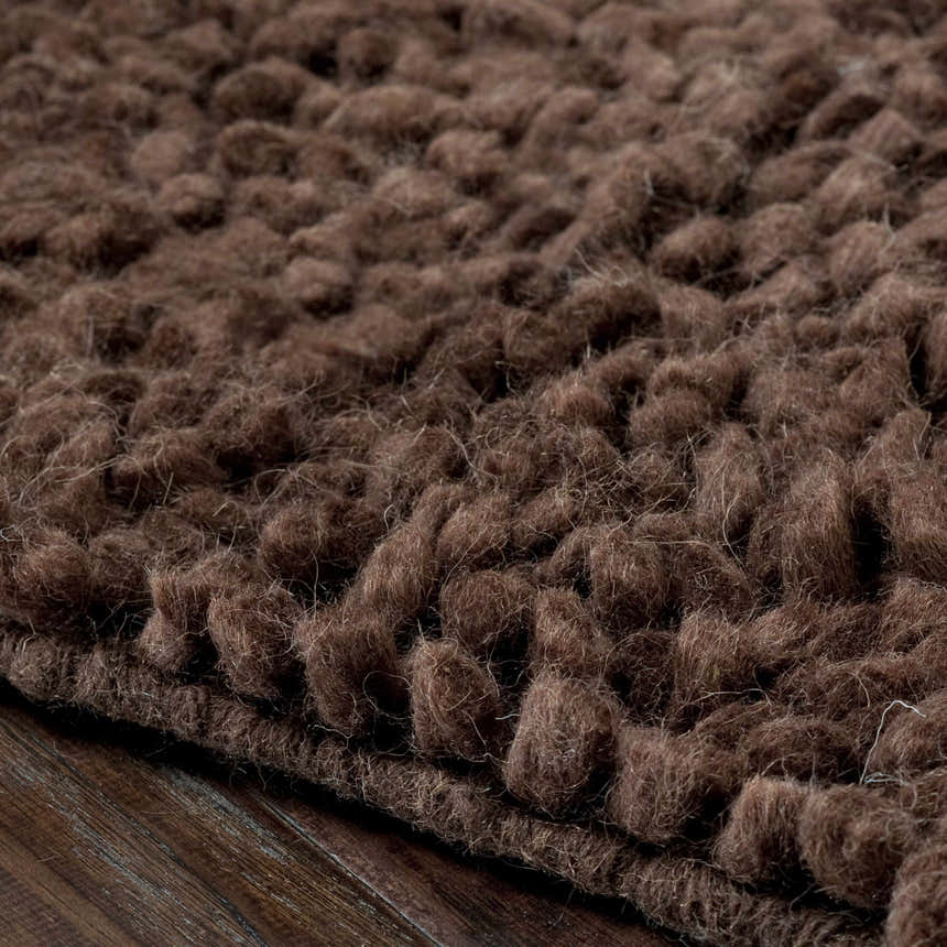 Close-up of the hand-woven Okawville Area Carpet. Dark brown, 100% wool rug with a textured, looped pile. Texture