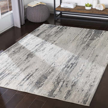Living room scene with a gray Oklaunion Faux Silk Rug, charcoal accents, dark wood floors, and a gray knit ottoman. Roomscene-Rectangle
