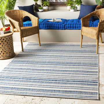 Coastal patio with wicker chairs and blue cushions, featuring the Olin White&Blue Striped Nordic Rug. Roomscene-Rectangle