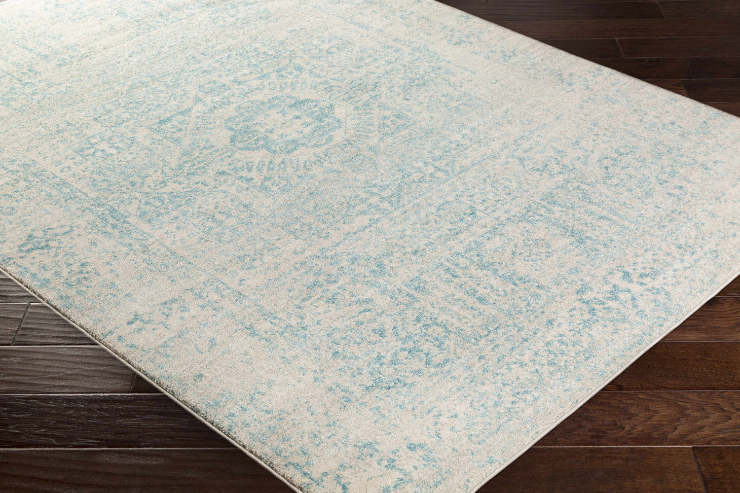 Close up of the Omega Area Rug - Clearance, light beige and teal vintage pattern. Corner