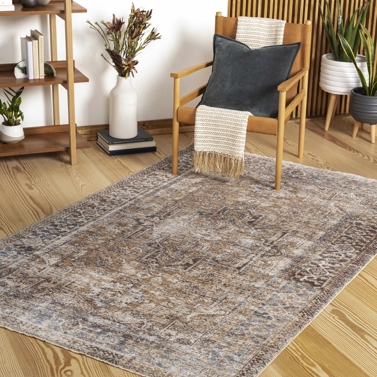 Living room scene with a Bohemian style Onley Area Rug in denim, gold, and beige tones under a leather chair. Roomscene-Rectangle