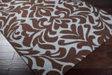 Close up of the Oppelo Area Rug, a hand woven wool rug in dark brown and sage with a contemporary floral pattern. Corner