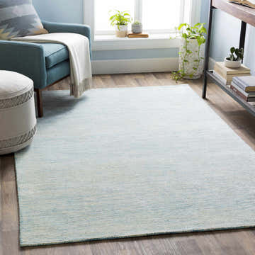 Living room scene with an Orcas Ice Blue rug, blue armchair, and wooden floor. Roomscene-Rectangle
