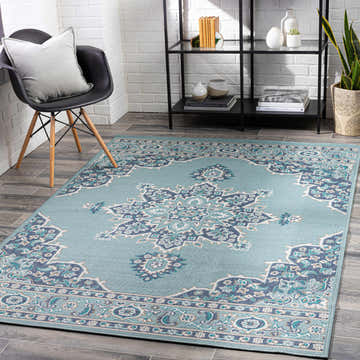 Entryway scene with Orla Pale Blue Medallion Area Rug, black chair, white brick wall, and black shelving unit. Roomscene-Rectangle