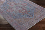 Close-up of the Otaki Washable Area Rug showing its traditional oriental pattern in dark gray, purple, brown, and natural gray tones. Corner